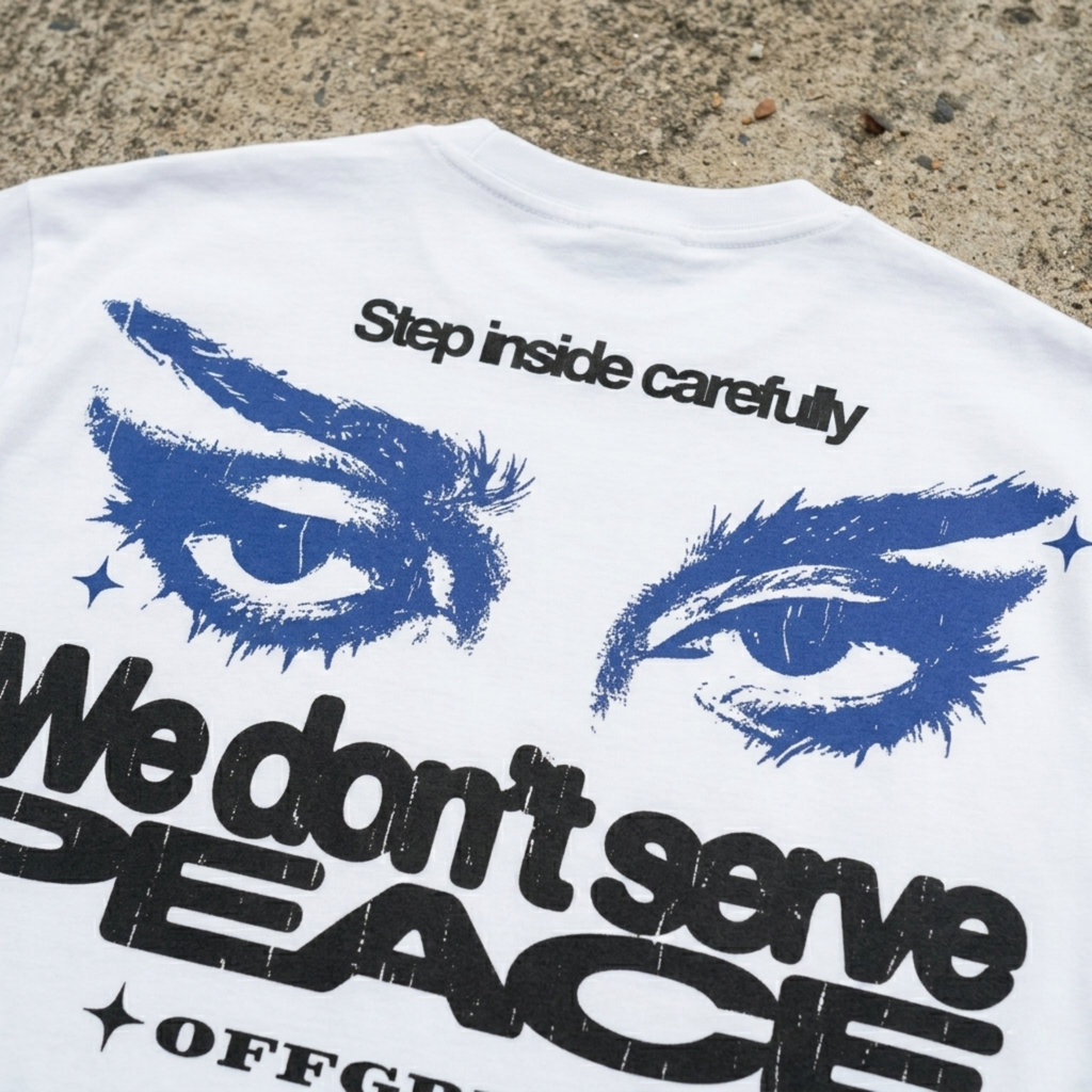 White t-shirt with blue eyes and text on a concrete surface