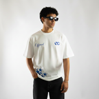 Person wearing a white t-shirt with logos on a plain background