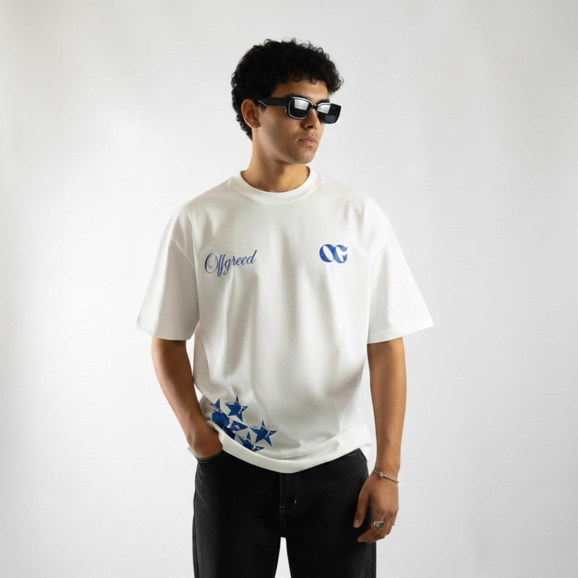 Person wearing a white t-shirt with logos on a plain background