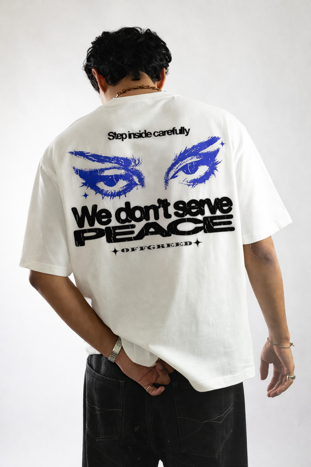 Person wearing a white t-shirt with graphic design and text on the back, standing against a plain background.