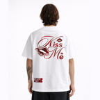 Person wearing a white t-shirt with 'Kiss Me' design on the back against a white background